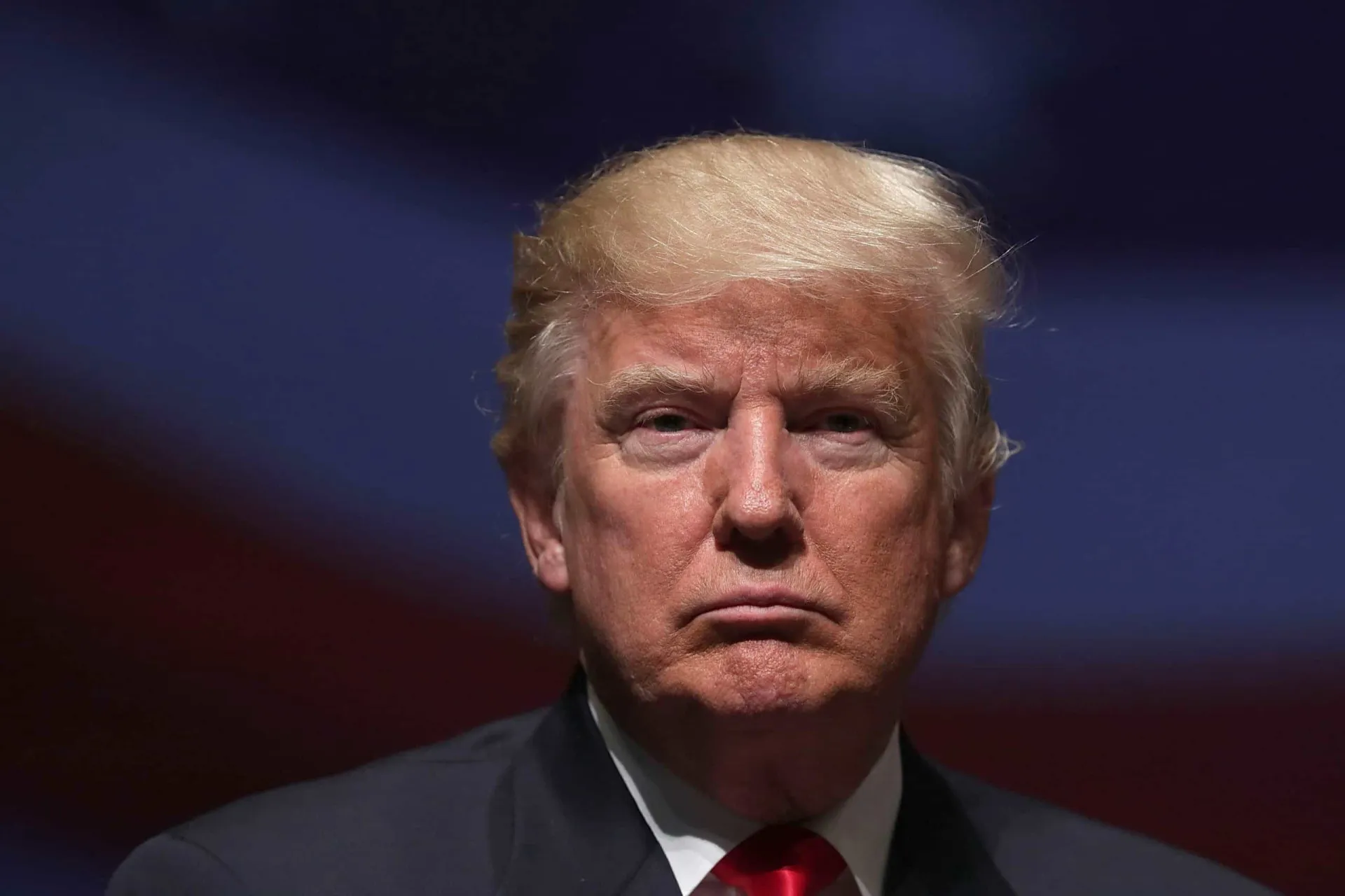 O ex-presidente Donald Trump acenando com um olhar sério.