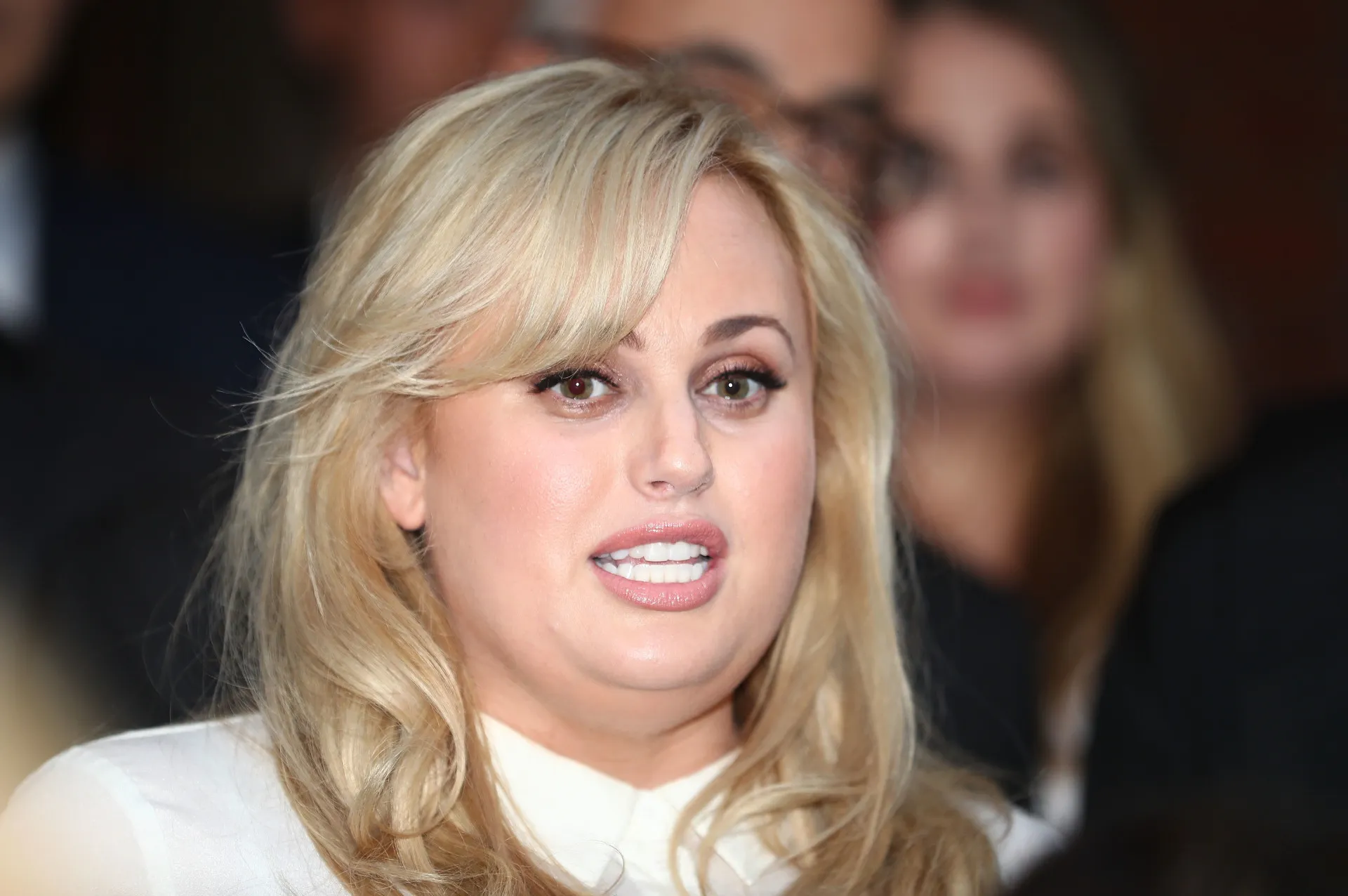 A atriz e comediante australiana Rebel Wilson sorrindo no tapete vermelho.