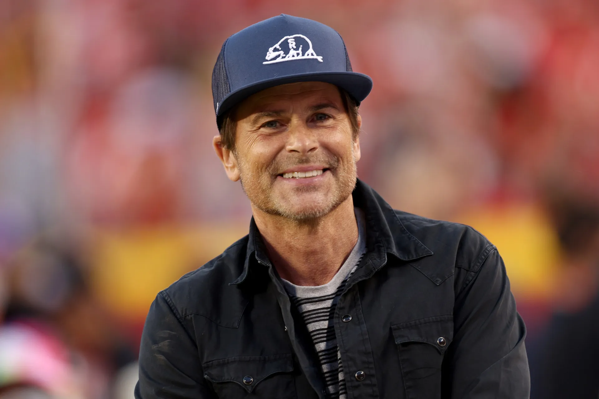 O ator Rob Lowe com seu sorriso característico de galã.