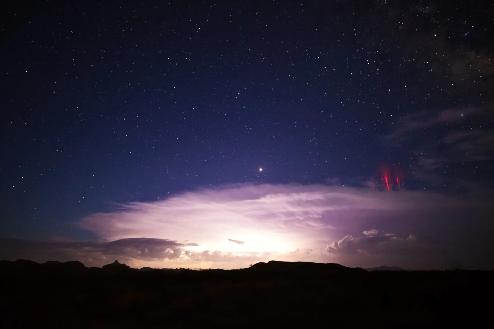 Estruturas de luz vermelha em forma de água-viva flutuando no espaço acima de nuvens de tempestade.