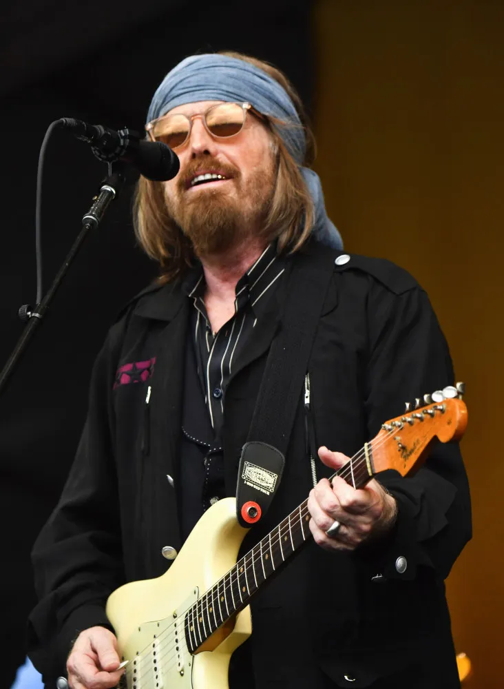 O roqueiro Tom Petty tocando guitarra durante um show.