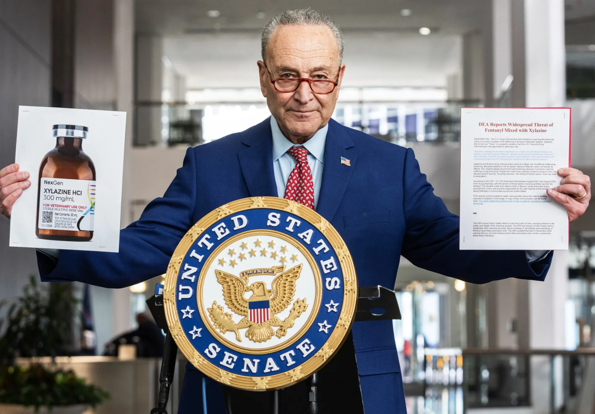 Senador Charles Schumer segurando uma foto de um frasco de xilazina durante coletiva de imprensa.