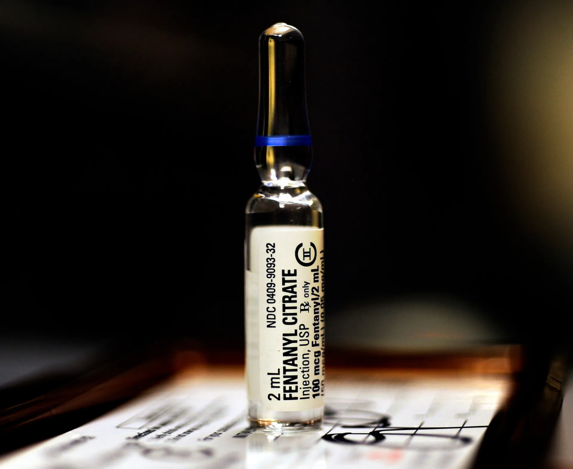 Mãos de um profissional de saúde segurando um frasco de fentanil, simbolizando seu poder.