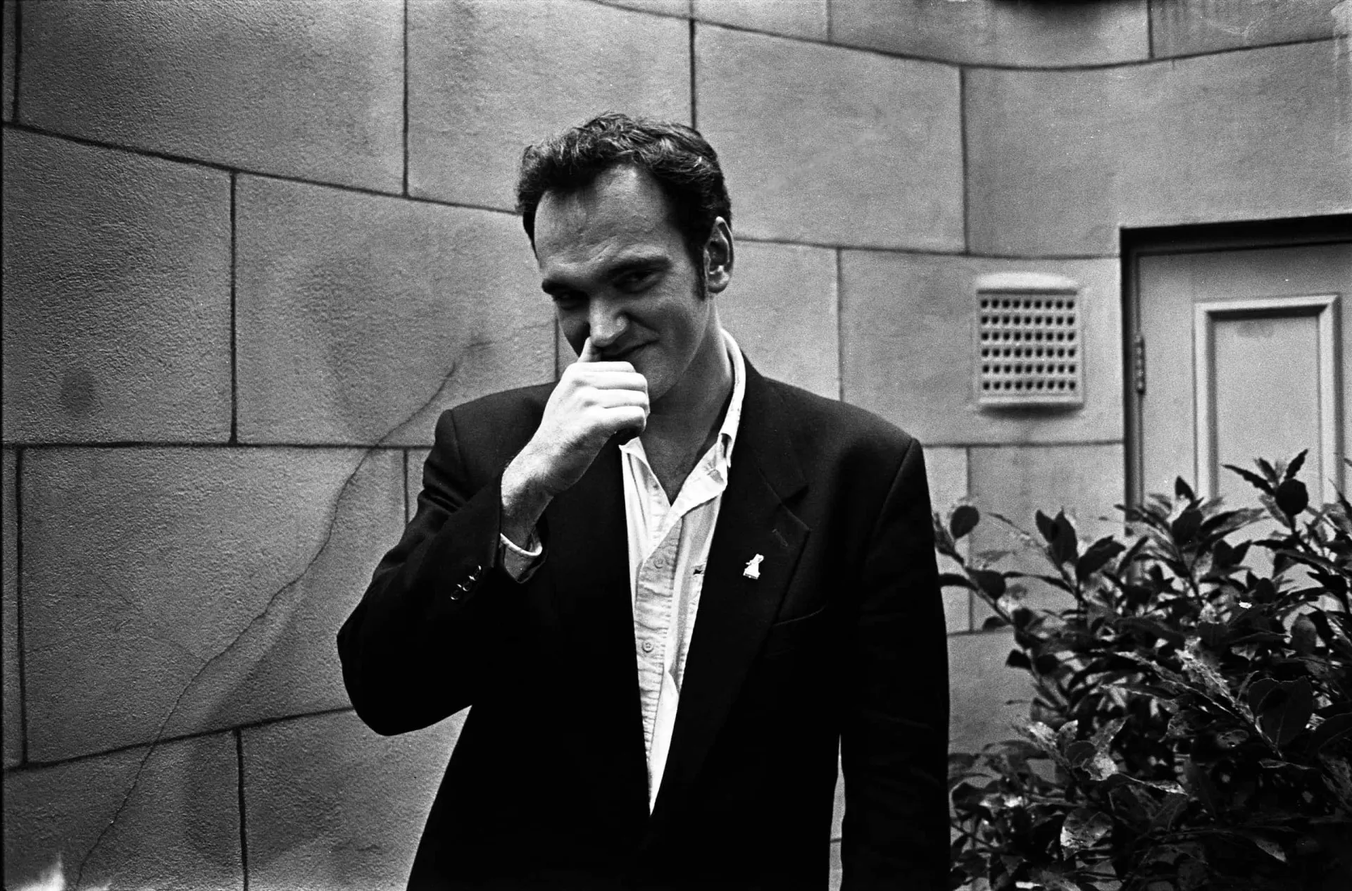 Quentin Tarantino jovem, com um sorriso característico, em seus primeiros anos de carreira.