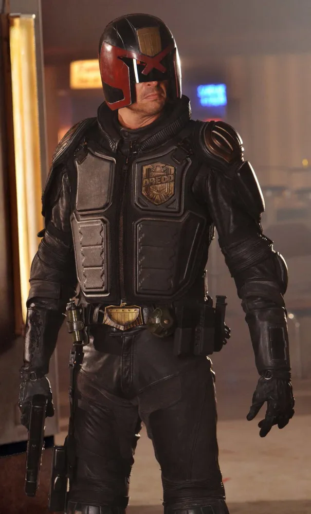 Karl Urban como o Juiz Dredd em uma cena sombria e violenta do filme de 2012.