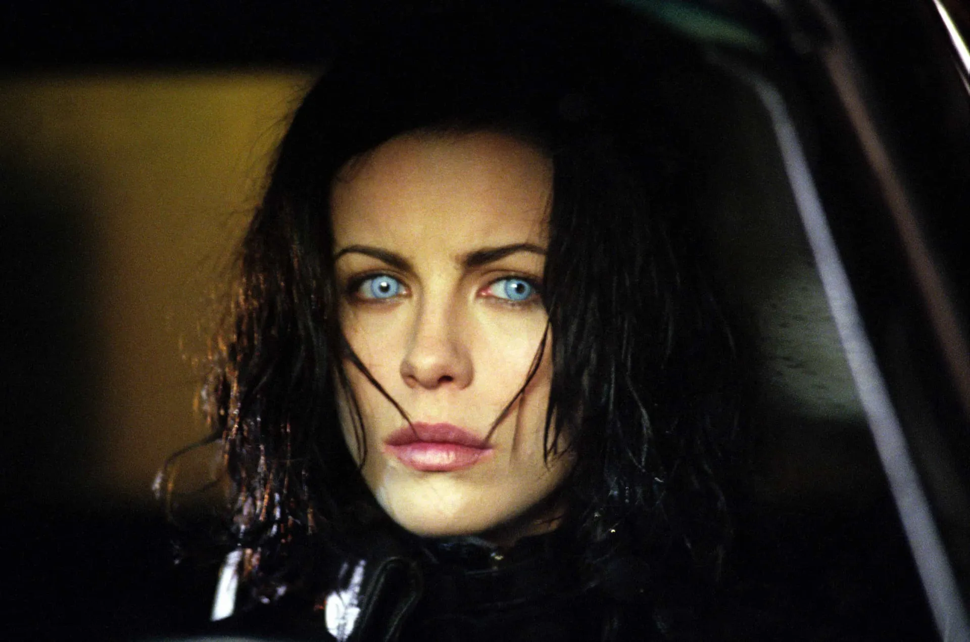 Kate Beckinsale como a vampira Selene, vestida de couro e segurando duas pistolas.