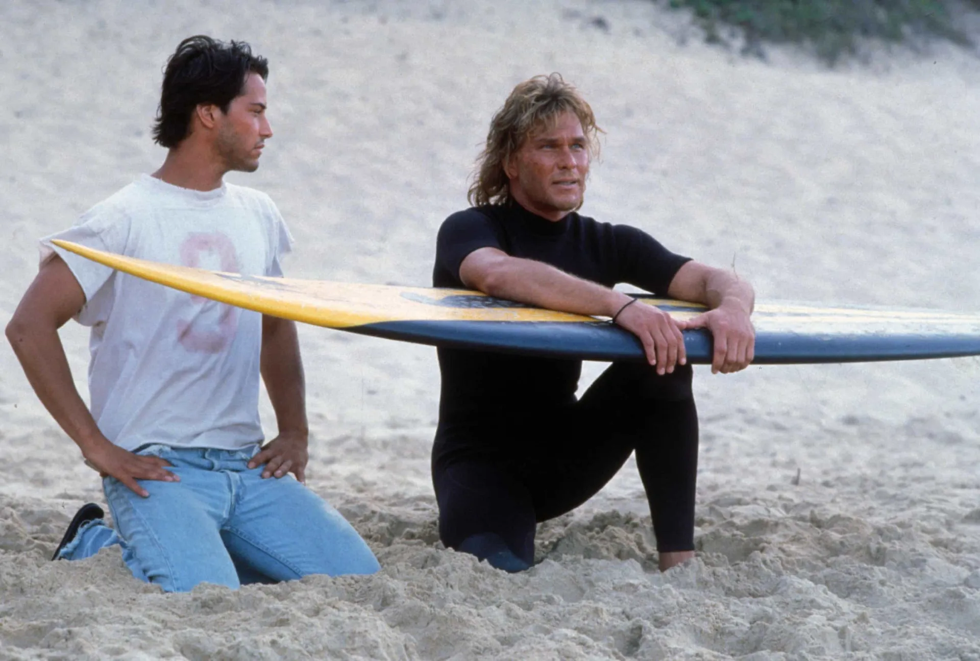Patrick Swayze e Keanu Reeves em cena de 'Caçadores de Emoção', mostrando a camaradagem dos personagens.