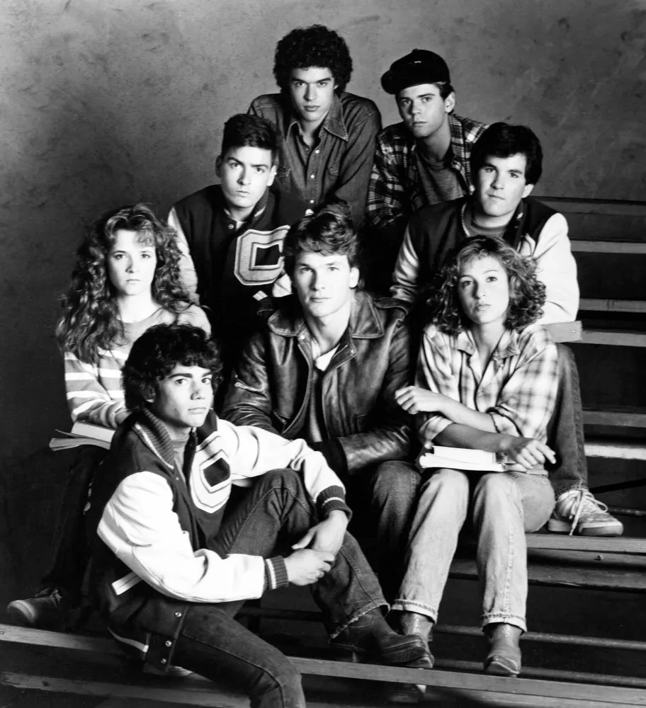 Jovens atores como Patrick Swayze e Charlie Sheen armados no filme 'Amanhecer Violento'.