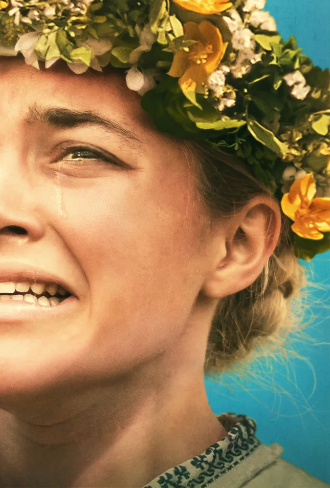 Florence Pugh como a 'Rainha de Maio' em 'Midsommar', cercada por um culto pagão sob a luz do dia.