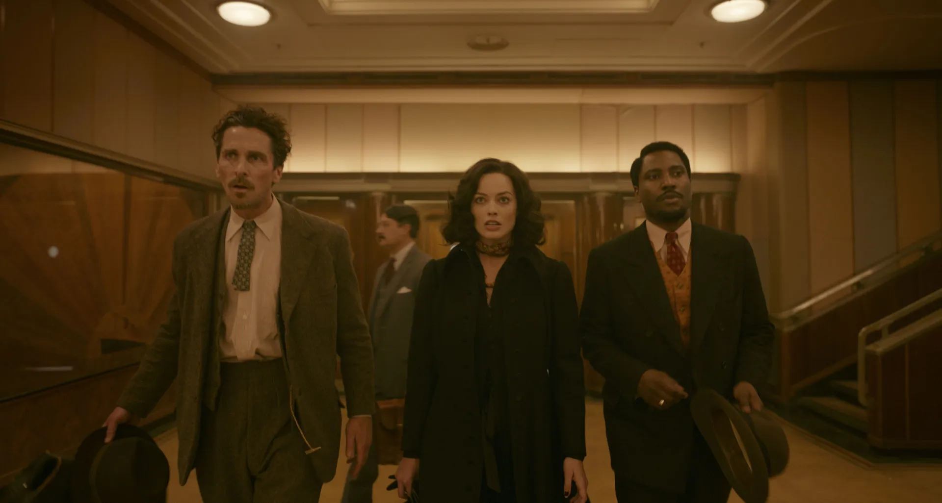 Elenco estelar de Amsterdam, incluindo Christian Bale, Margot Robbie e John David Washington, com expressões confusas.