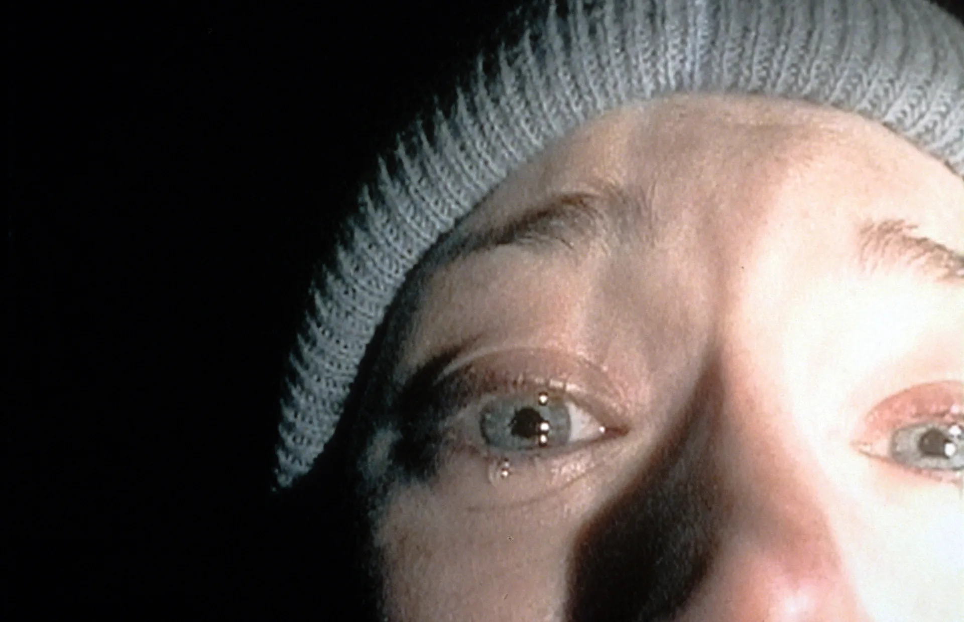 Close-up do rosto assustado de uma das personagens de 'A Bruxa de Blair', uma imagem icônica do 'found footage'.