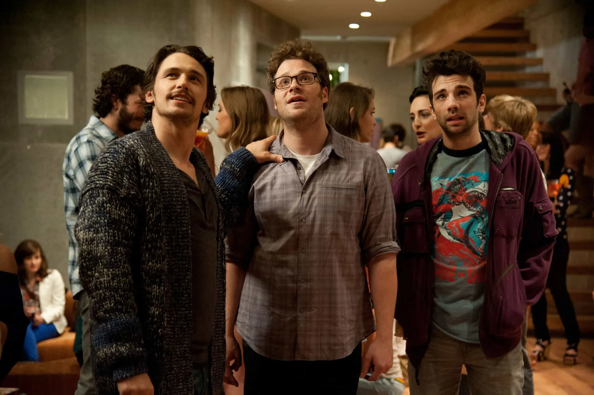 Elenco de comediantes do filme 'É o Fim' olhando para o céu durante o apocalipse.