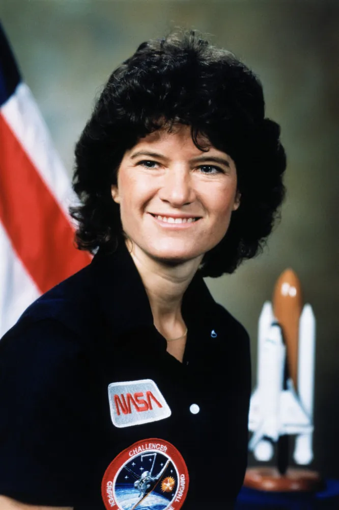 A astronauta Sally Ride sorrindo em seu traje espacial, um símbolo de pioneirismo e coragem.