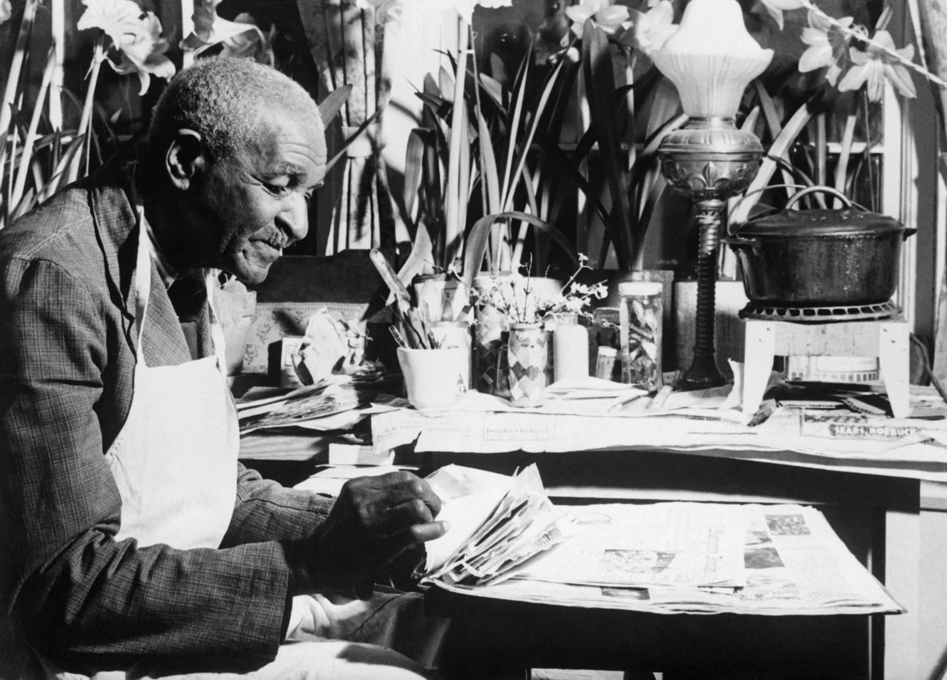 George Washington Carver em seu laboratório, analisando plantas, demonstrando sua dedicação à ciência agrícola.