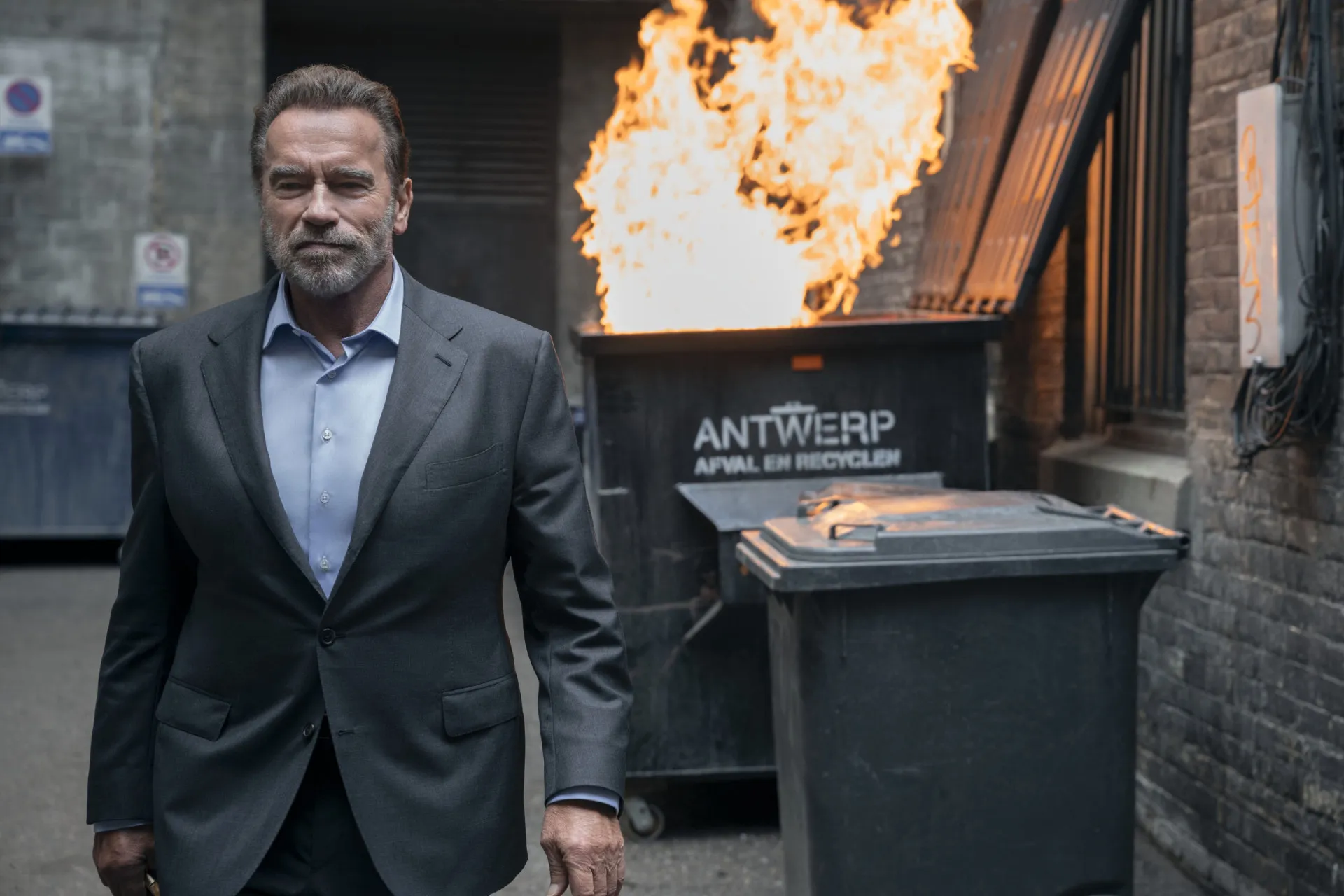Arnold Schwarzenegger mais velho, com cabelos grisalhos e barba, sorrindo em um evento.