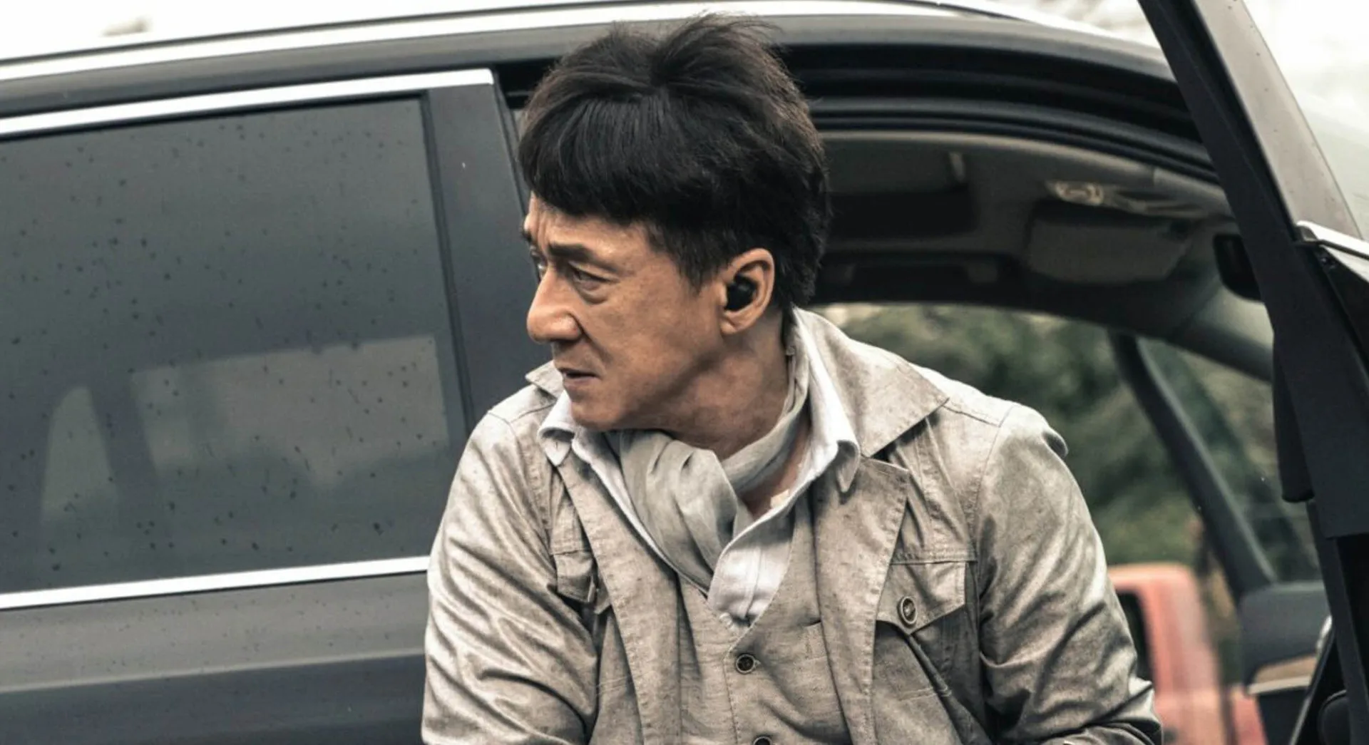 Jackie Chan mais velho, sorrindo em um evento, com um ar de lenda viva do cinema.