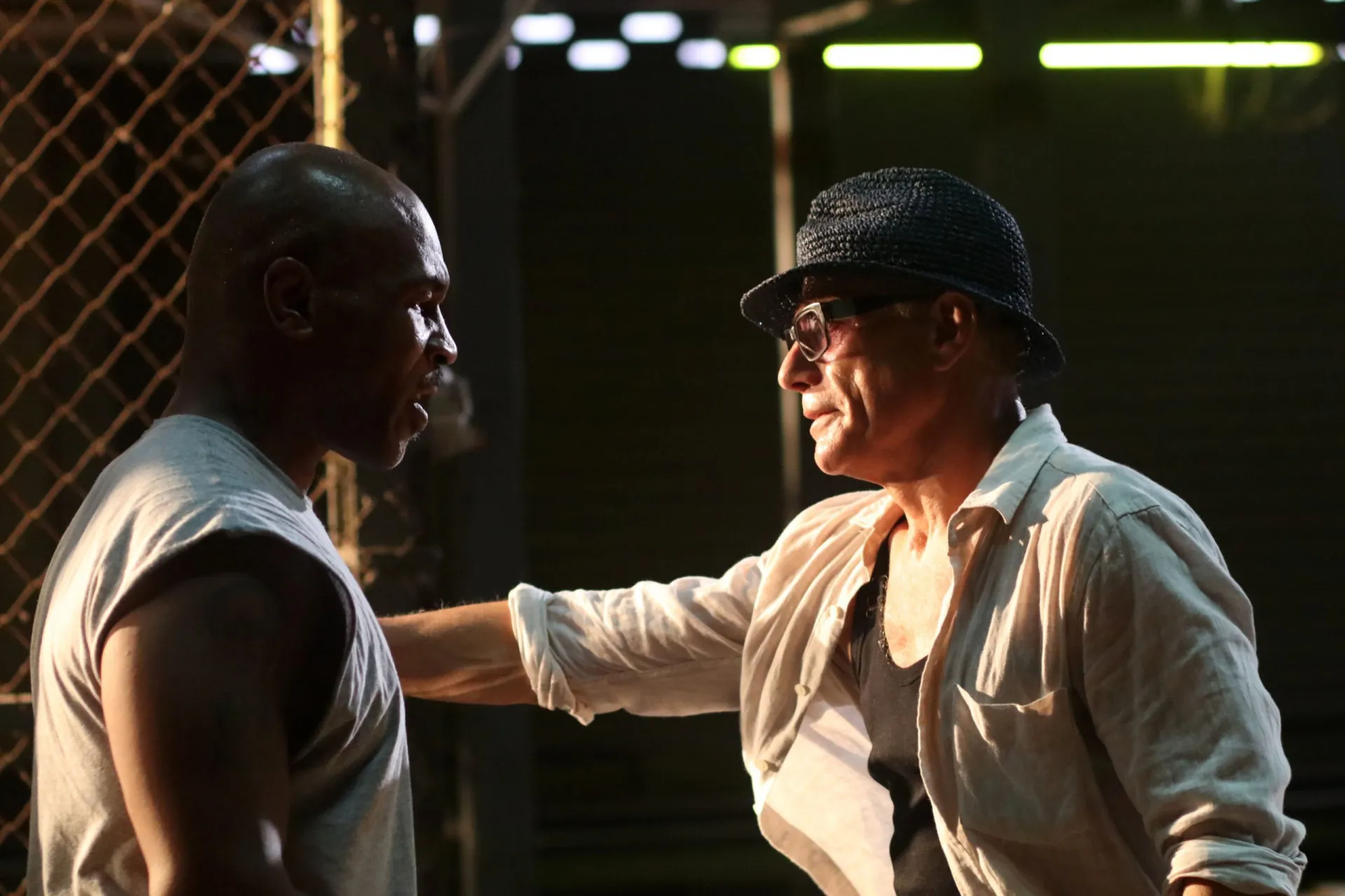 Jean-Claude Van Damme mais velho, de terno e óculos escuros, com um visual mais maduro.
