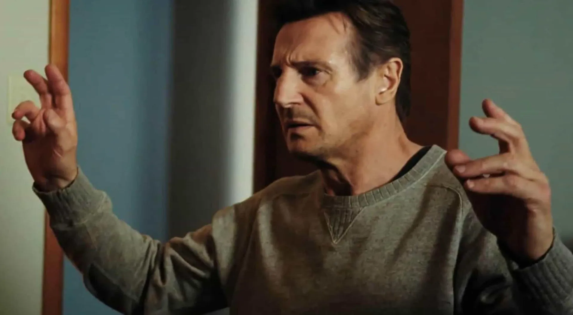 Liam Neeson mais jovem, com um olhar sério e intenso, antes de se tornar um astro de ação.