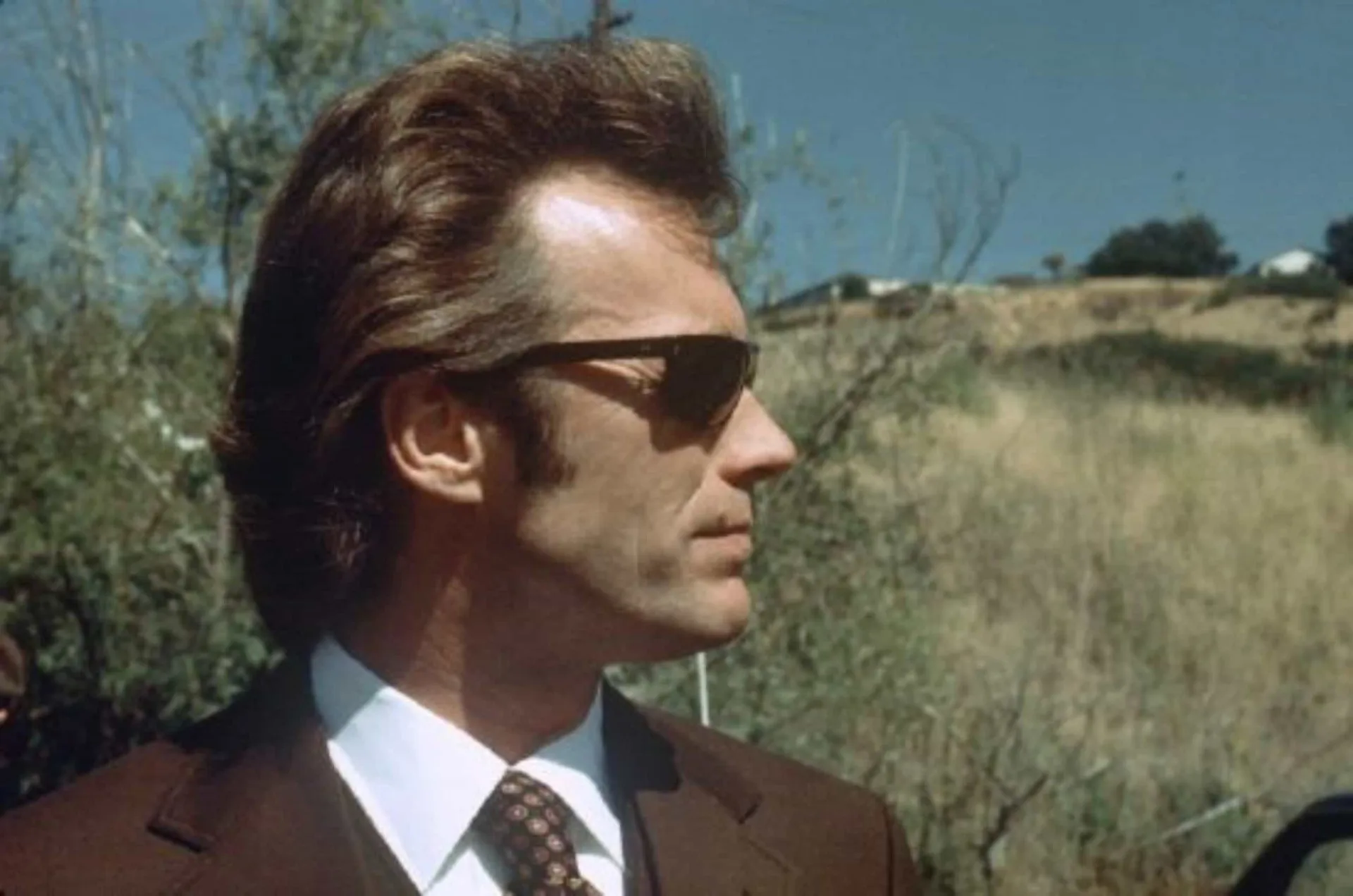 Clint Eastwood jovem, como o 'Homem Sem Nome', com poncho, chapéu e o cigarro no canto da boca.