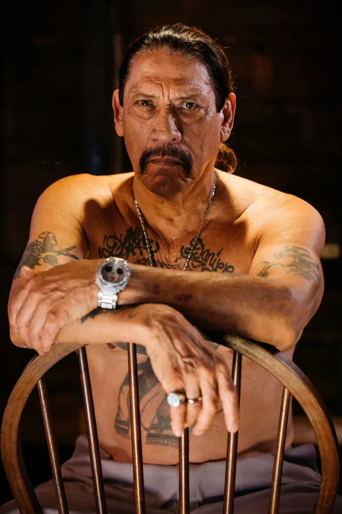 Danny Trejo mais velho, sorrindo, com o cabelo grisalho preso para trás e seu bigode marcante.