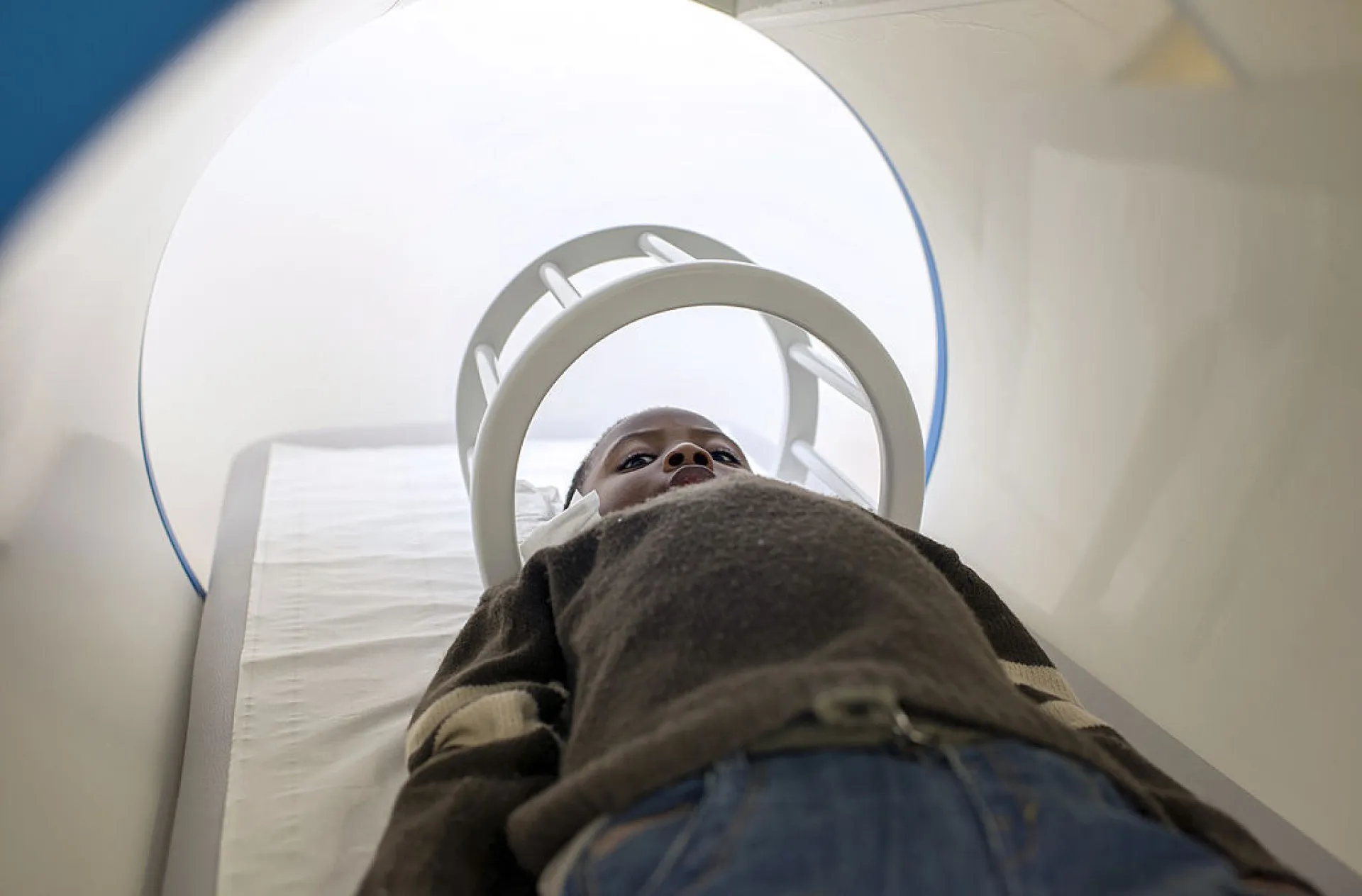 Paciente dentro de uma máquina de ressonância magnética, com gráficos de atividade cerebral sobrepostos.