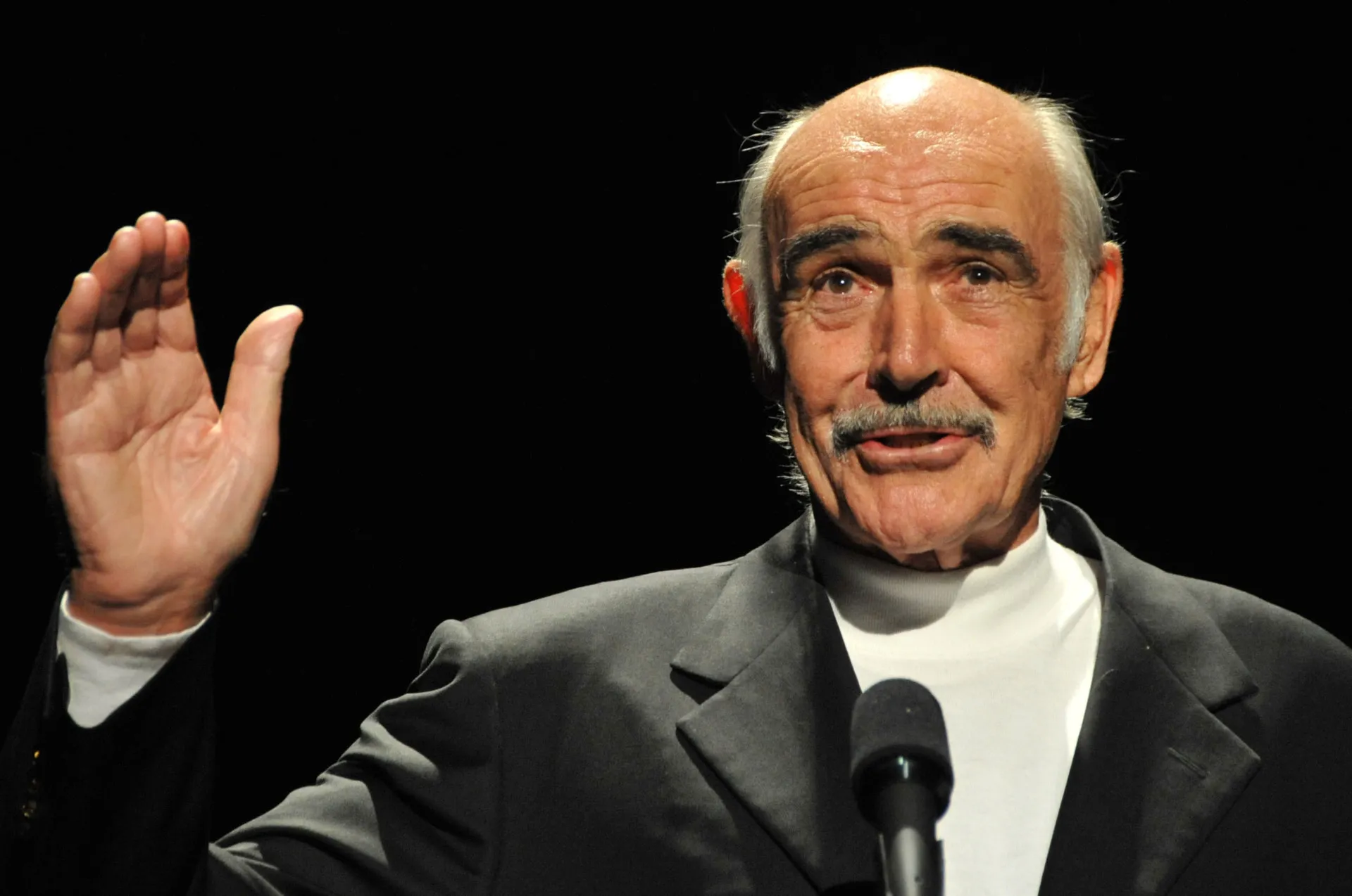 Sean Connery com seu sorriso charmoso, personificando o icônico James Bond.