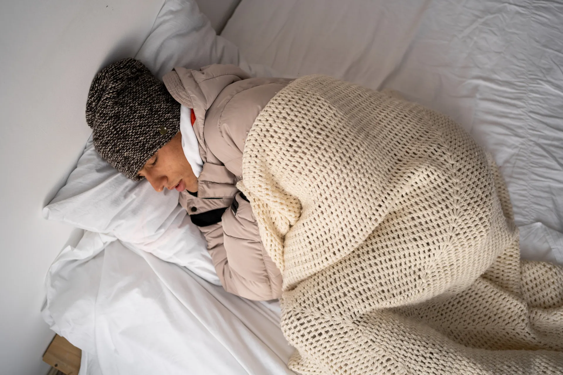 Pessoa com aparência sonolenta e com frio, enrolada em um cobertor.