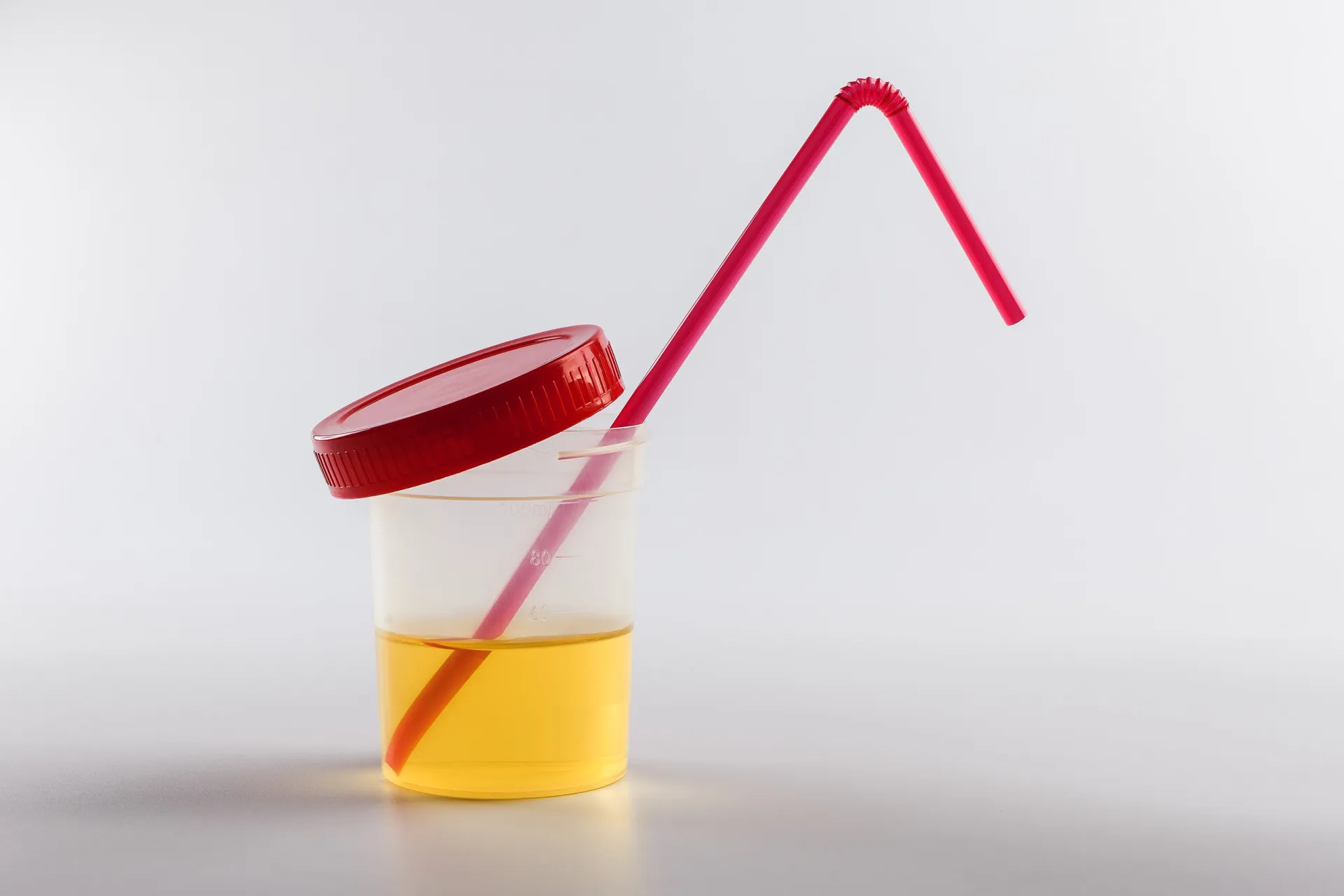 Copo de plástico transparente contendo um líquido amarelo.