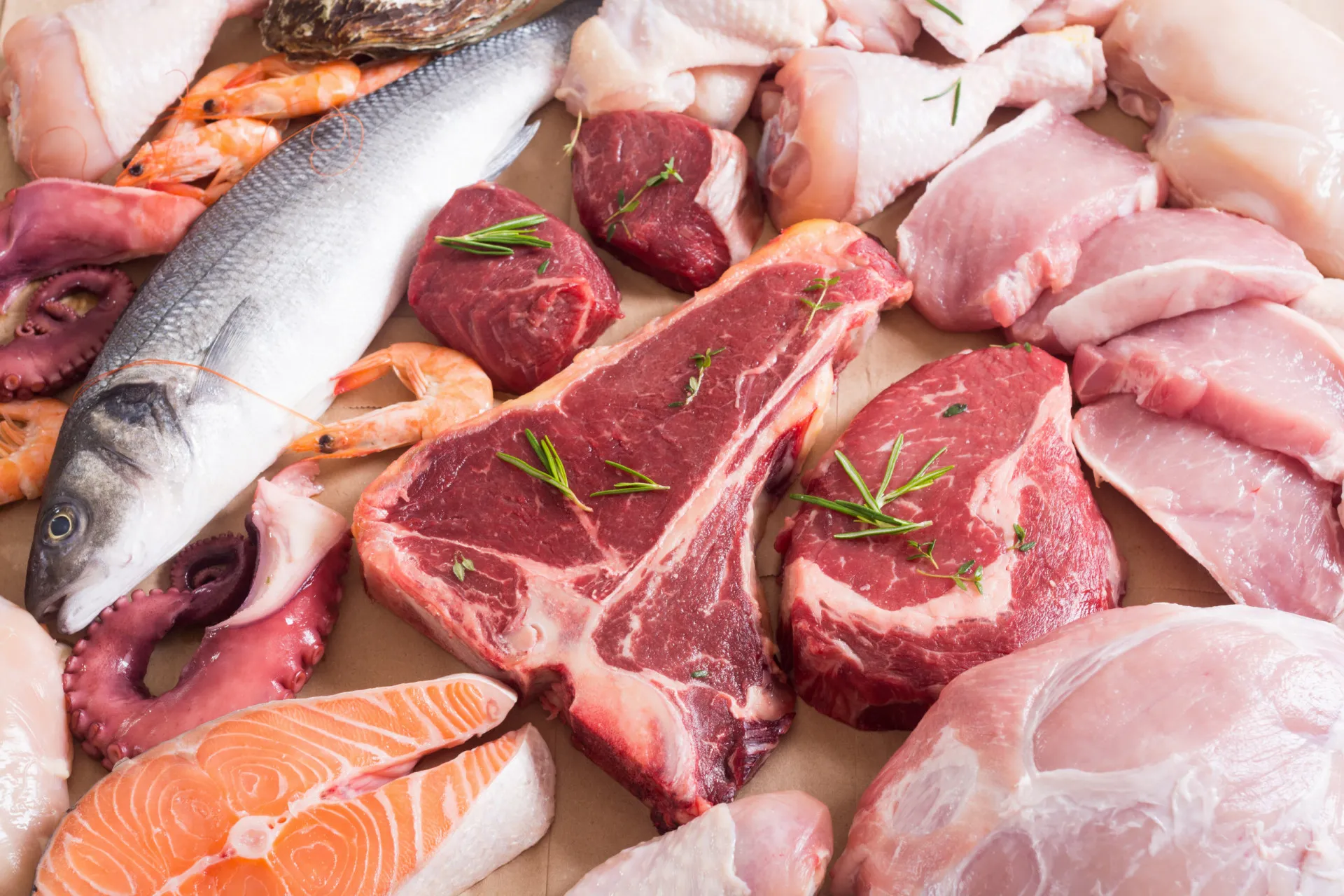 Pedaços de carne crua e peixe cru em uma tábua de madeira.