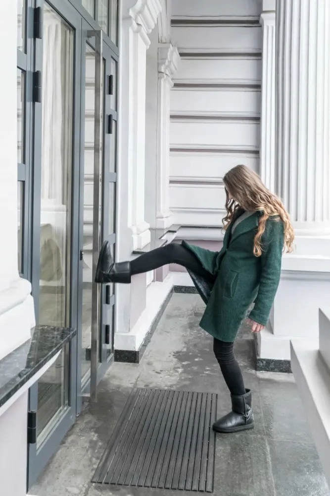 Uma bota prestes a chutar e arrombar uma porta de madeira fechada.
