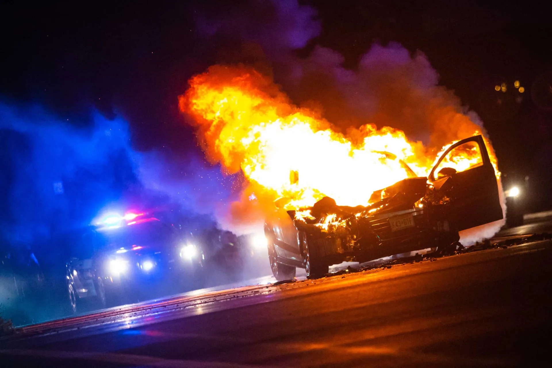 Um carro explodindo em uma bola de fogo gigante após ser atingido por tiros.