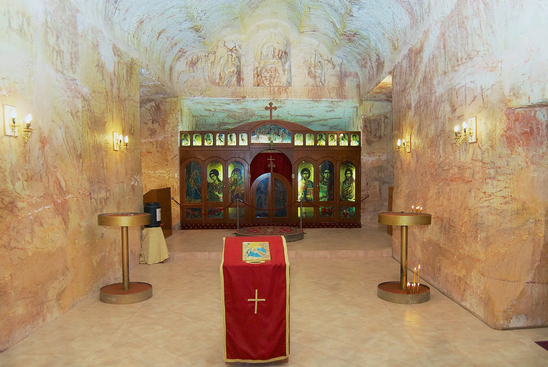 Interior de uma igreja subterrânea em Coober Pedy, com um altar e bancos.