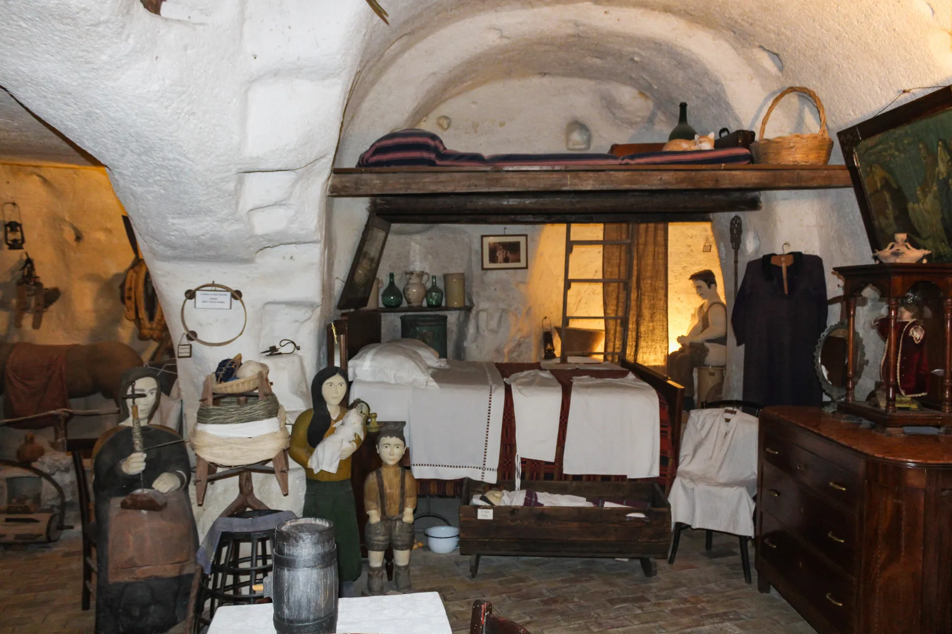 Réplica histórica do interior de uma casa-caverna em Matera, com móveis simples.