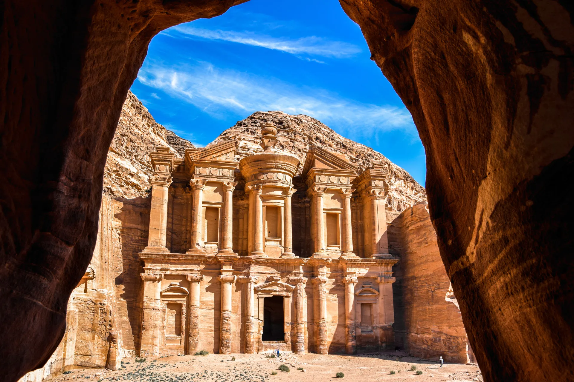 A icônica fachada do Tesouro (Al-Khazneh) em Petra, vista através de um desfiladeiro estreito.