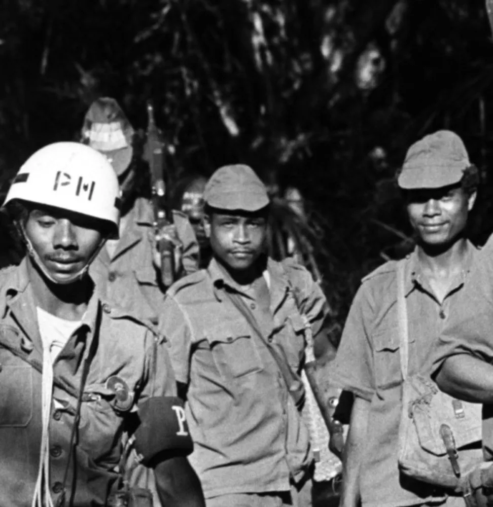 Manifestantes timorenses segurando a bandeira de Timor Leste durante uma marcha pela independência.