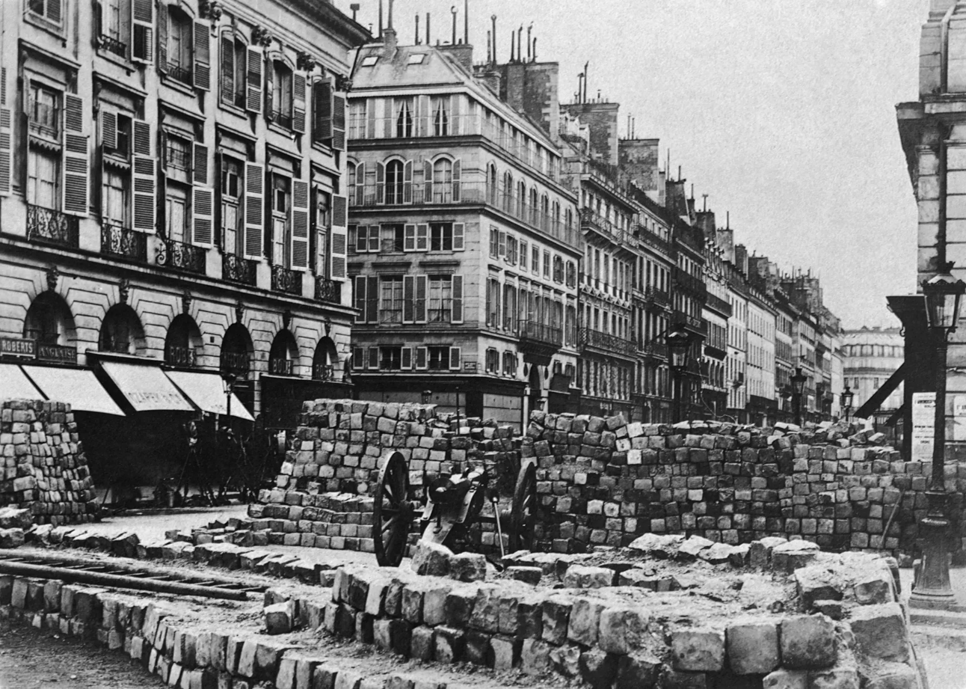 Pintura histórica retratando uma barricada durante a Comuna de Paris, com revolucionários em combate.