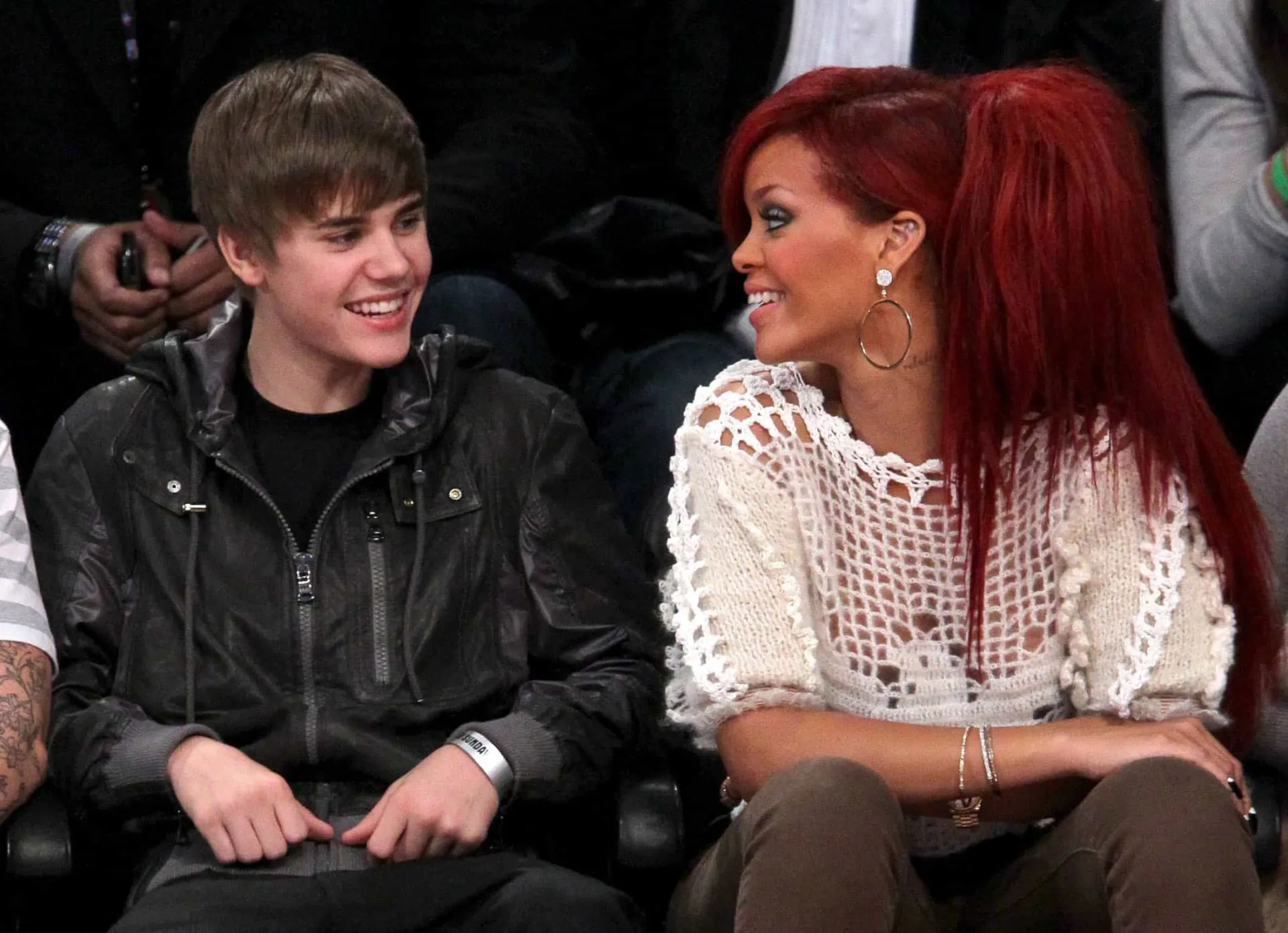 Justin Bieber mais jovem e Rihanna posando em um evento.