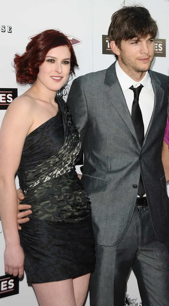 Rumer Willis posando em um evento e Ashton Kutcher sorrindo.