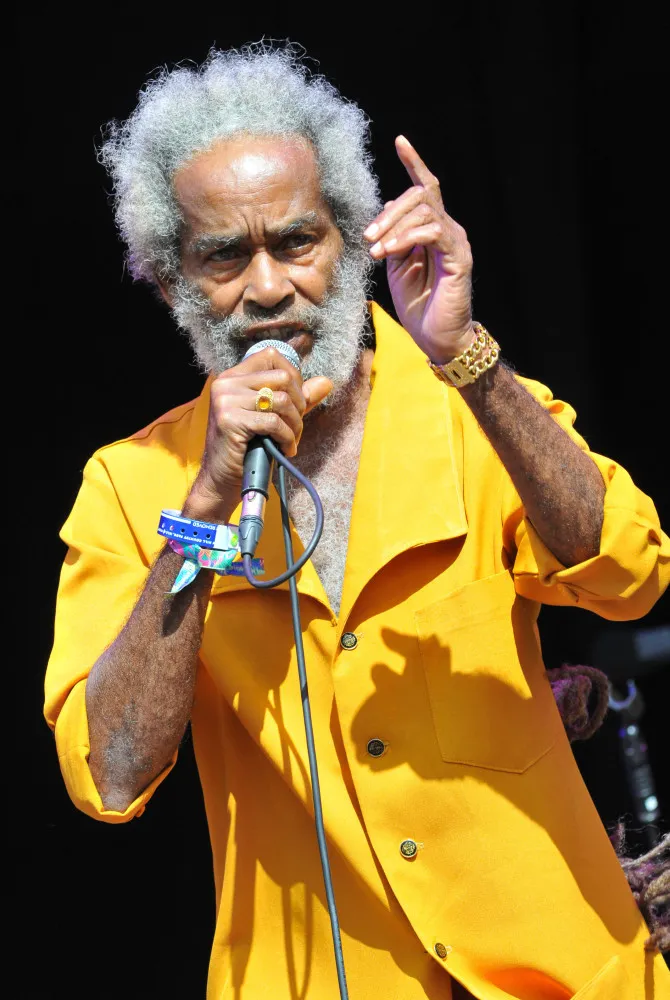 O cantor de reggae Max Romeo durante uma performance, cantando com paixão.