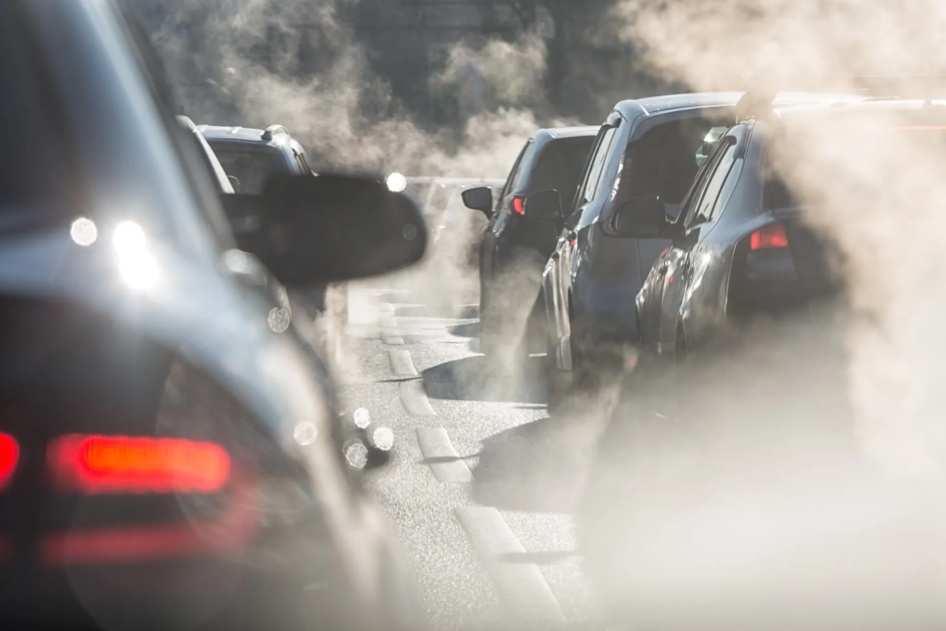 Fila de carros em um engarrafamento, com fumaça visível saindo dos escapamentos.