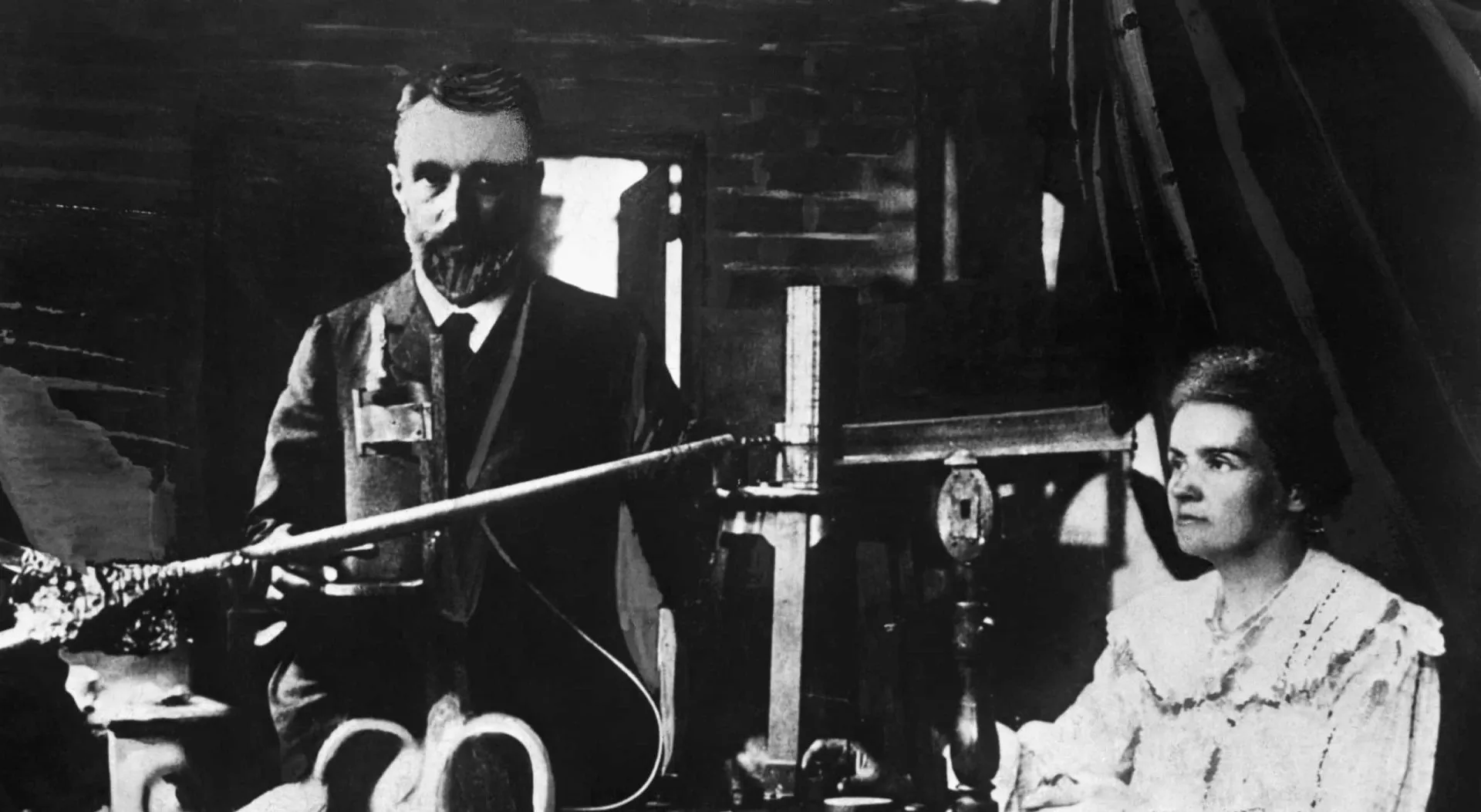 Marie e Pierre Curie em seu laboratório, pioneiros no estudo da radioatividade.