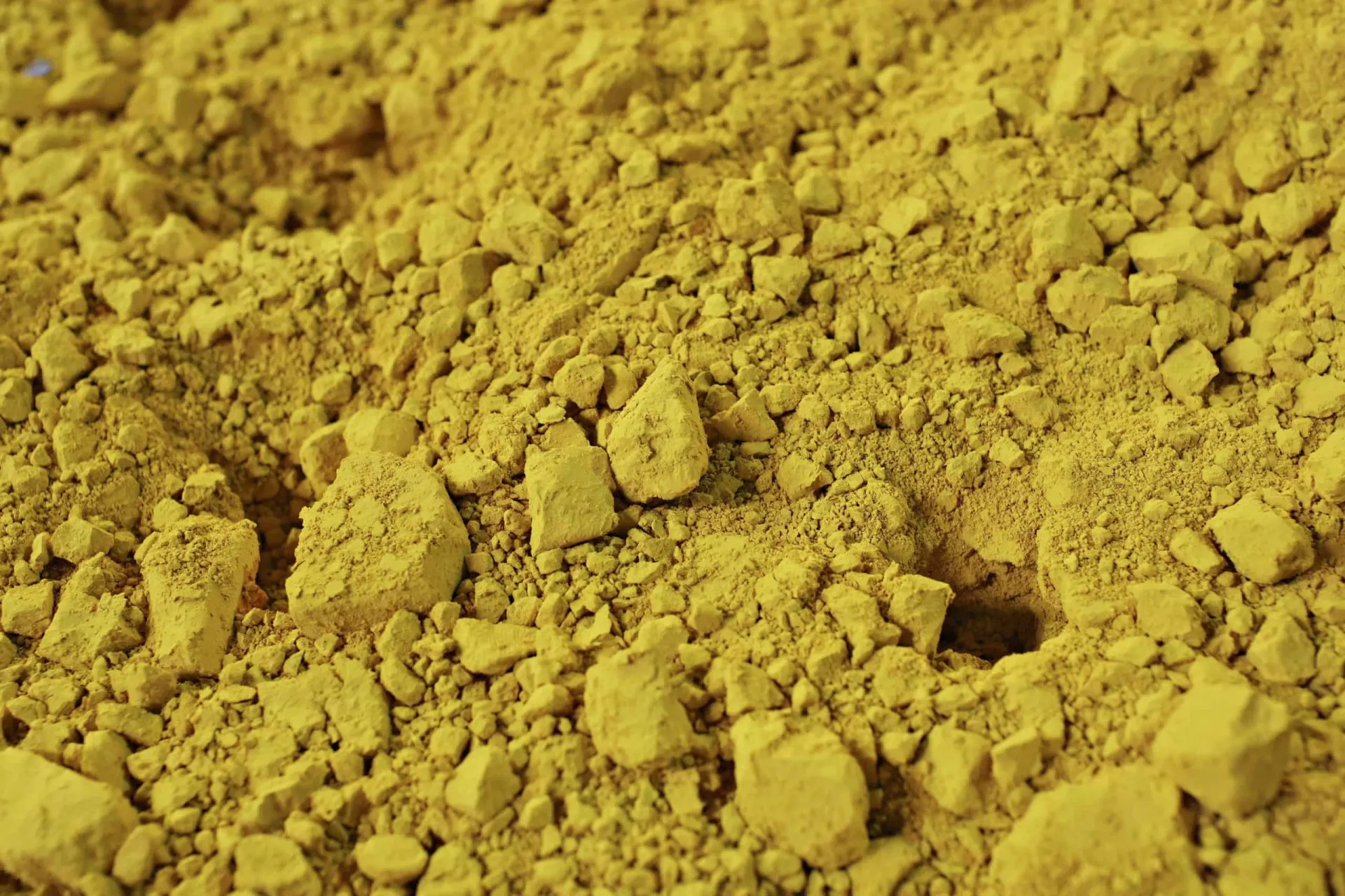 Pó de 'yellowcake' (óxido de urânio) sendo manuseado, a matéria-prima da indústria nuclear.