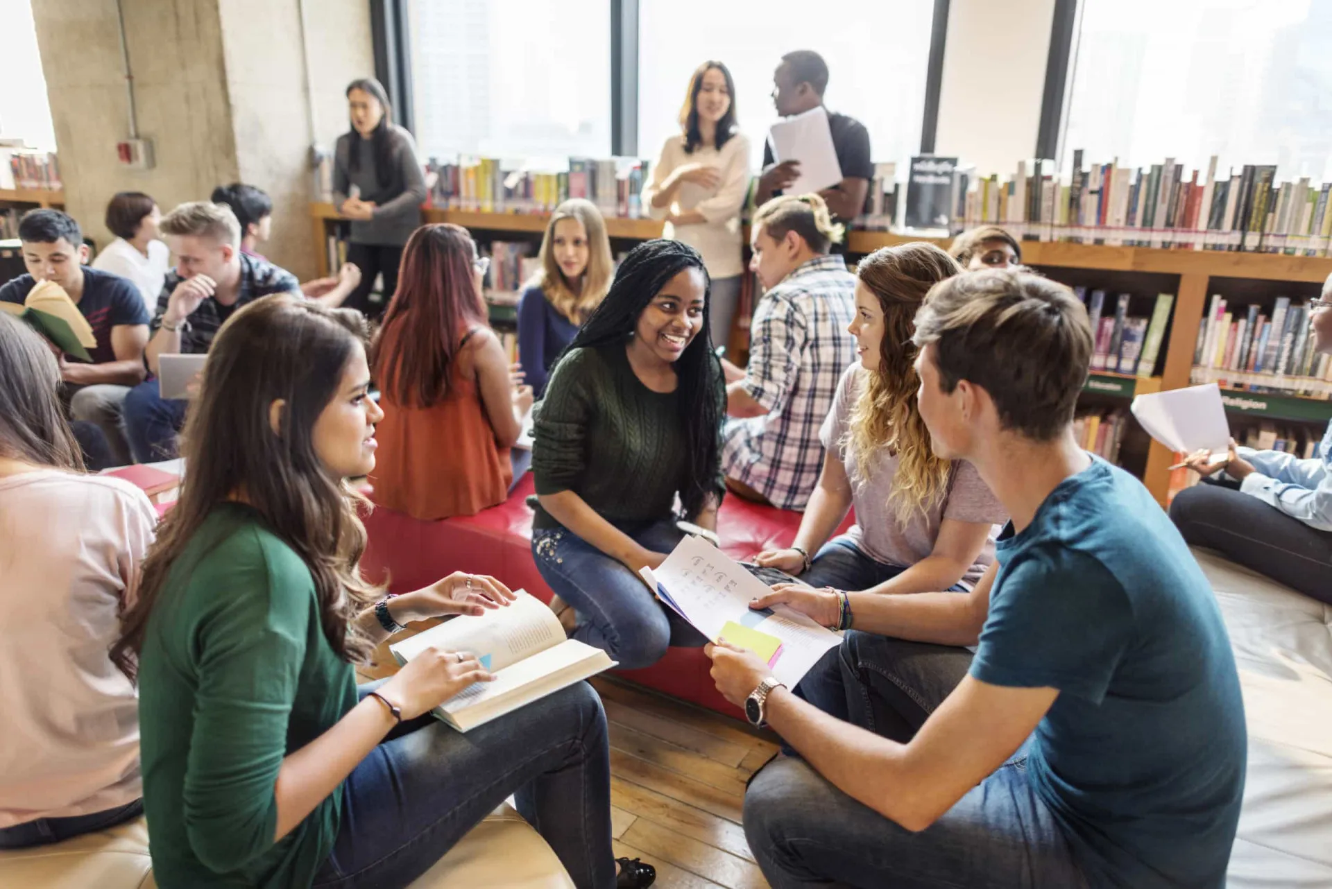 Grupo de estudantes universitários focados em seus livros em uma biblioteca.