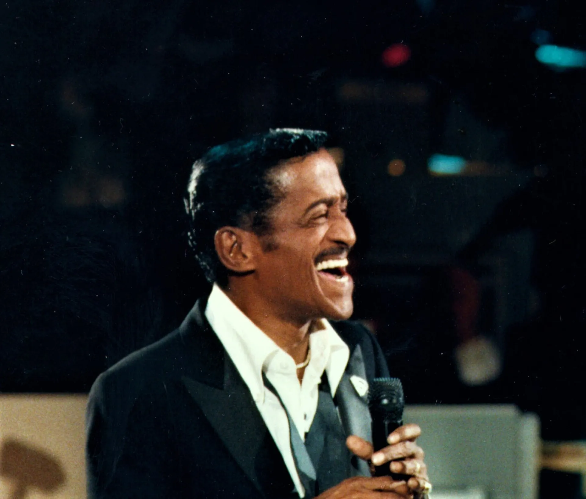 O artista Sammy Davis Jr. sorrindo e fumando, exalando carisma e talento.
