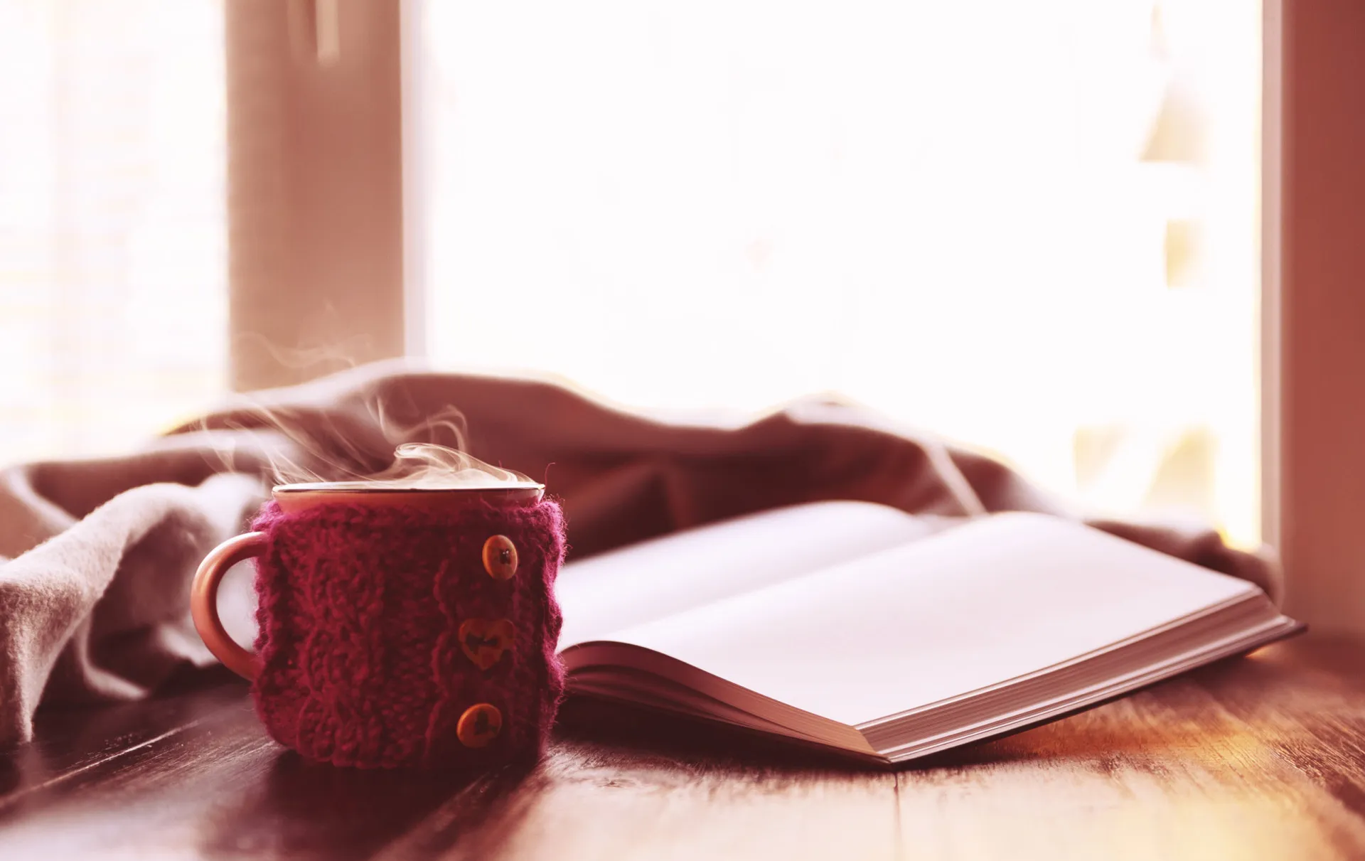 Pessoa lendo um livro em um ambiente aconchegante, com uma janela mostrando uma paisagem de inverno.