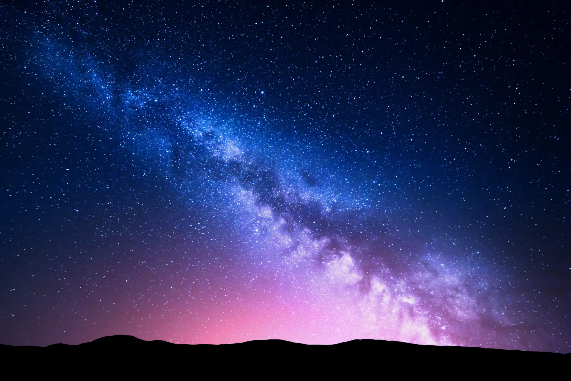 Céu noturno estrelado sobre uma paisagem de inverno com montanhas.