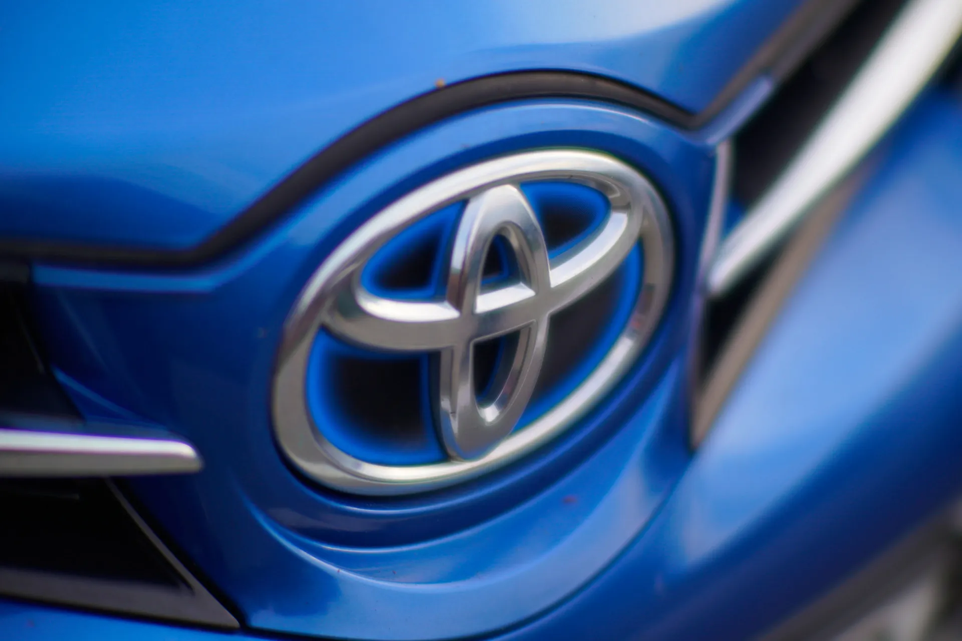 O logotipo prateado da Toyota na grade frontal de um de seus carros.