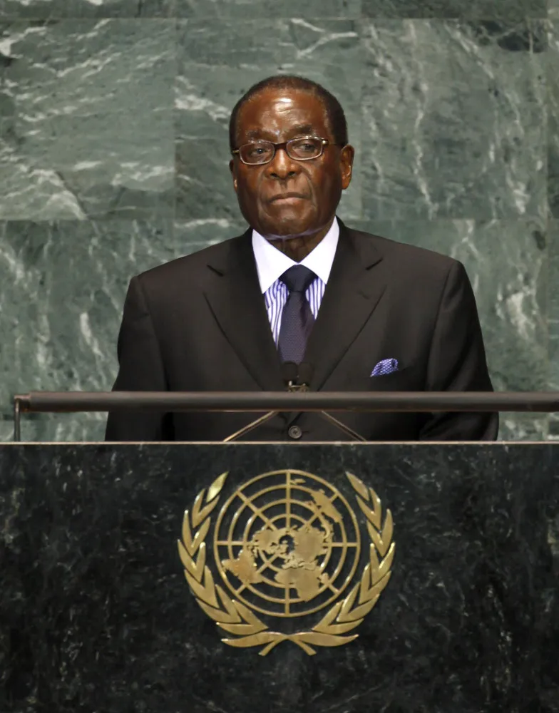 Robert Mugabe, ex-presidente do Zimbábue, falando em um pódio, com expressão determinada.