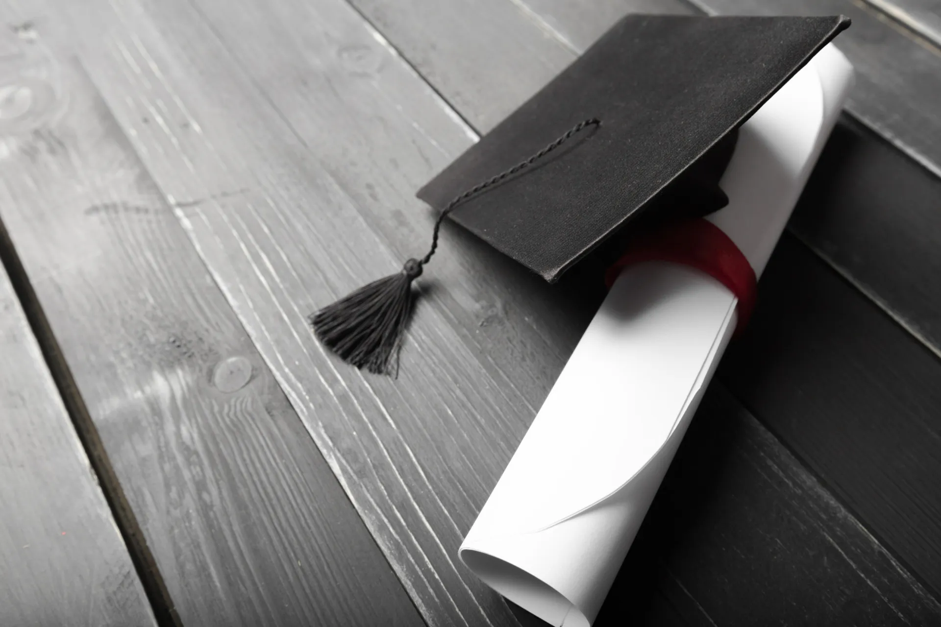 Uma pessoa segurando um diploma universitário enrolado com uma fita, simbolizando a conquista acadêmica.