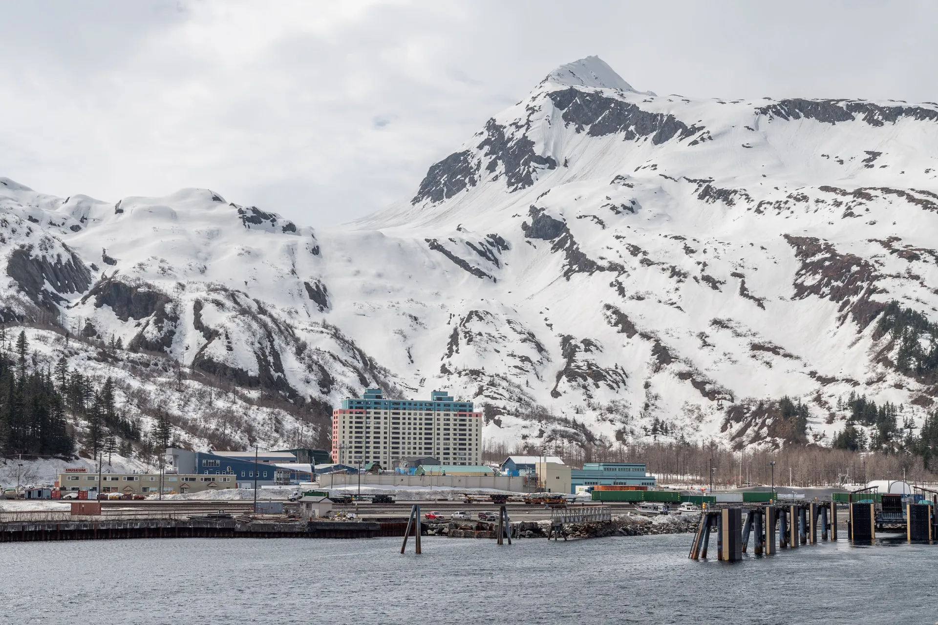 O prédio Begich Towers em Whittier, Alasca, uma grande estrutura de concreto isolada em uma paisagem de neve e montanhas.